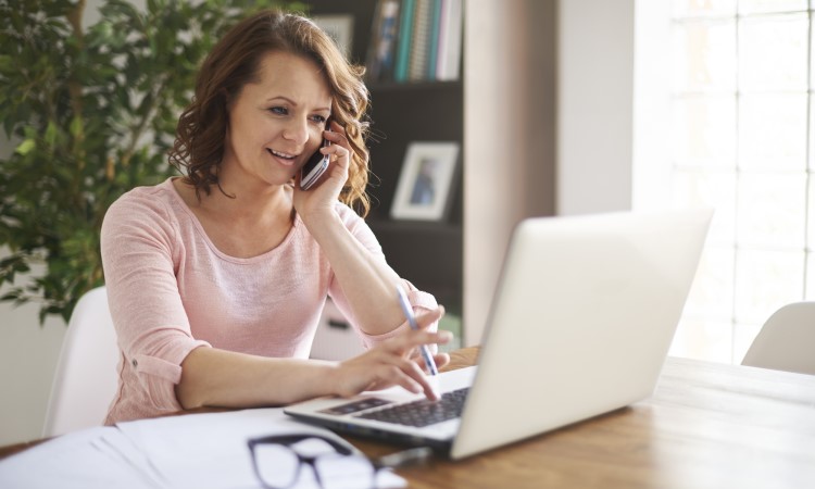 frau-als-freiberuflerin-telefoniert freiberufliche Frau telefoniert während der Arbeit am Computer